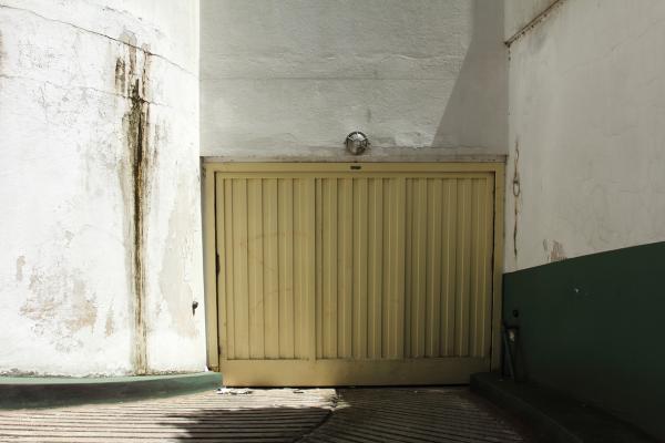 garage, mancha en la pared, sol de mediodia, media luz, media sombra. frontal